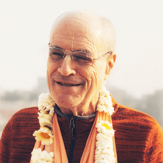 His Grace Bir Krishna Das Goswami in a serene temple setting, wearing traditional saffron robes and radiating spiritual warmth